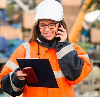 A construction worker using a tablet and a telephone